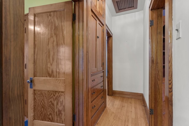 hall featuring visible vents, light wood-style flooring, and baseboards