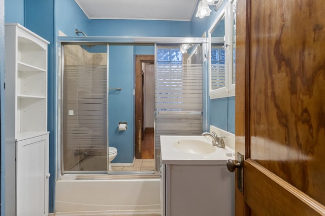 bathroom featuring toilet, combined bath / shower with glass door, and vanity