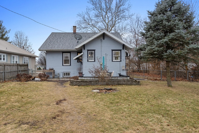 back of house featuring a chimney, fence, a lawn, and roof with shingles