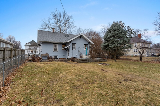 back of house featuring a fenced backyard, a chimney, and a lawn