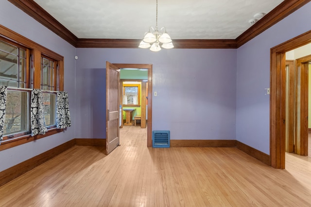 empty room featuring crown molding, visible vents, hardwood / wood-style floors, a chandelier, and baseboards