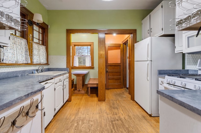 kitchen with dark countertops, white cabinets, dishwasher, and a sink