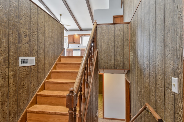 stairway with wood walls, visible vents, and beamed ceiling