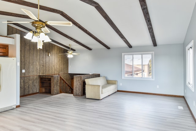 unfurnished room featuring vaulted ceiling with beams, wooden walls, baseboards, and wood finished floors