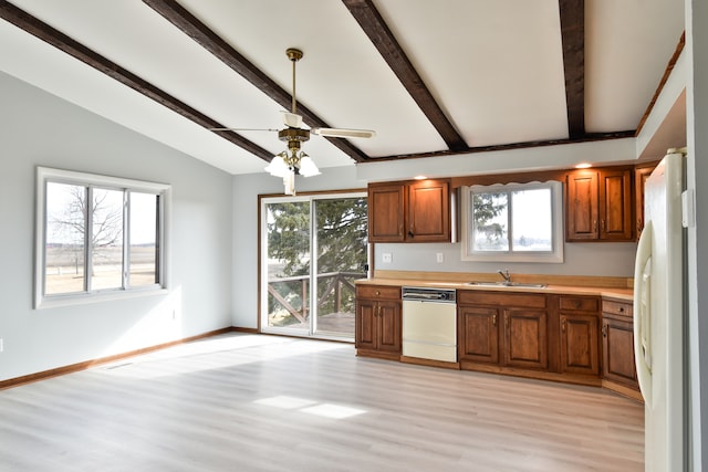 kitchen with white appliances, brown cabinetry, lofted ceiling with beams, light countertops, and a sink