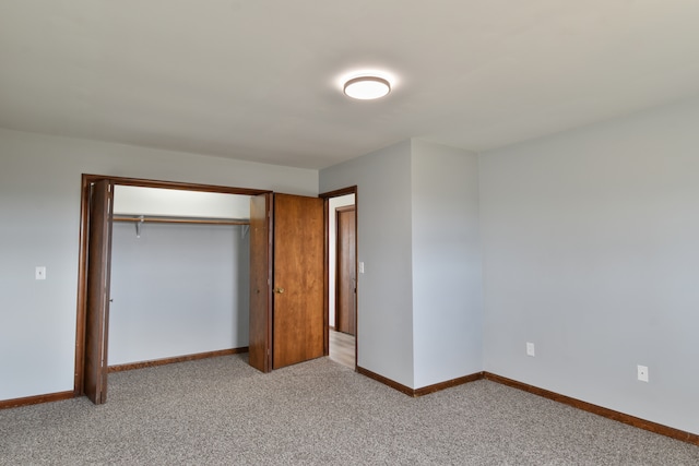 unfurnished bedroom featuring light carpet, a closet, and baseboards