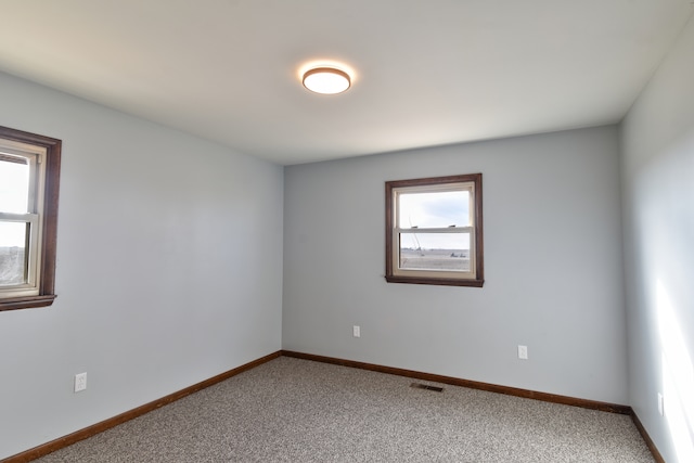 empty room featuring light carpet, visible vents, and baseboards