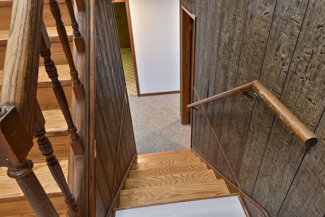 stairs featuring carpet and wood walls