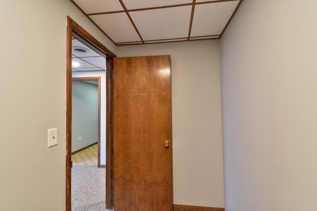 hallway featuring carpet floors, a paneled ceiling, and visible vents