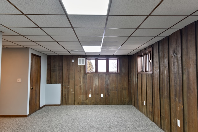 below grade area featuring carpet floors, visible vents, and wood walls