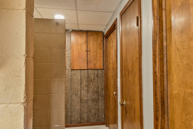 interior details with concrete block wall and a paneled ceiling