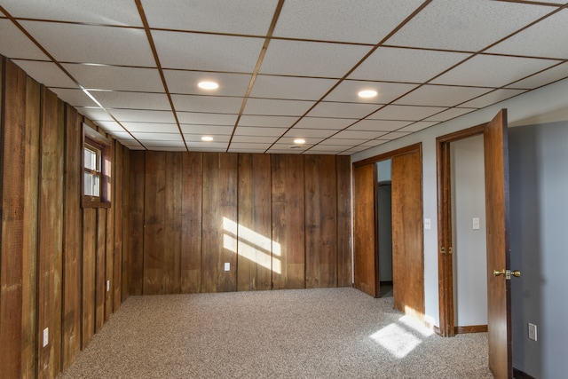 carpeted spare room featuring wooden walls and recessed lighting