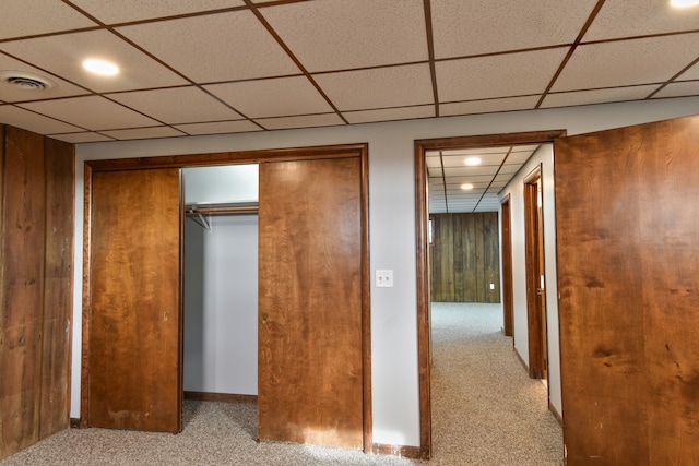 unfurnished bedroom with carpet floors, wood walls, a closet, and visible vents