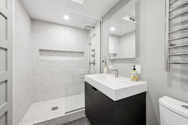 bathroom featuring vanity, toilet, and a tile shower