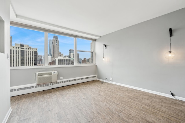 spare room featuring a baseboard heating unit, hardwood / wood-style floors, and a wall mounted AC