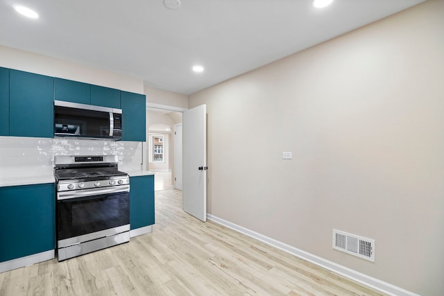 kitchen featuring tasteful backsplash, stainless steel appliances, blue cabinets, and light wood-type flooring