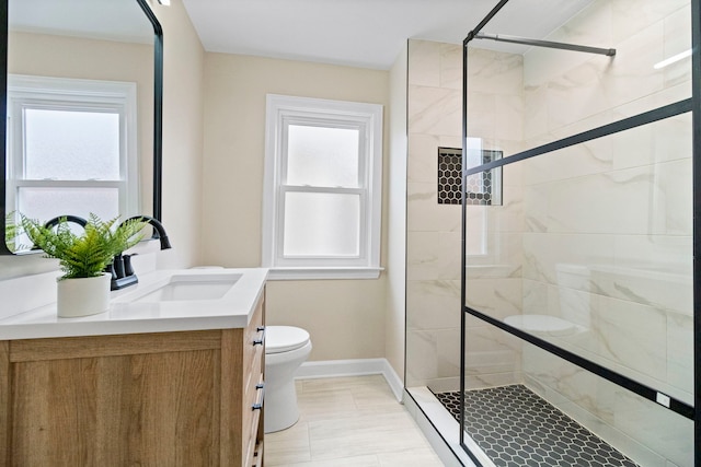 bathroom featuring toilet, vanity, and a shower with shower door