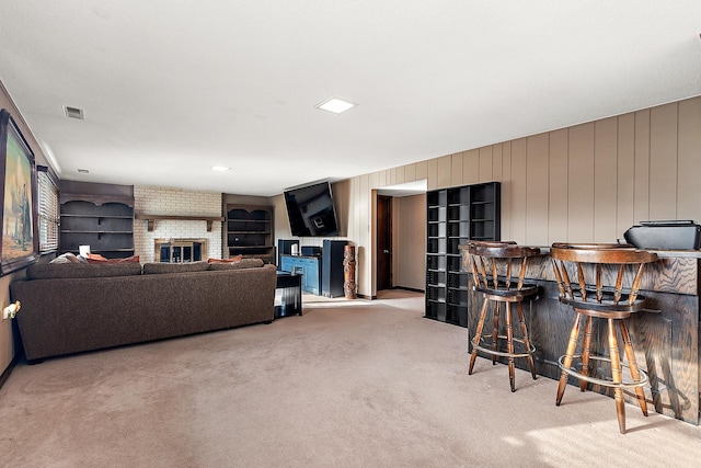 carpeted living room with a brick fireplace and indoor bar