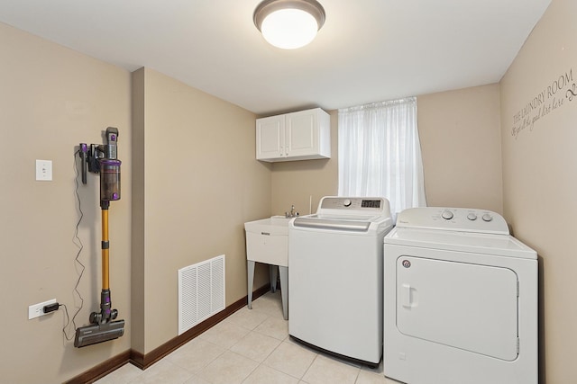 laundry room featuring separate washer and dryer, light tile patterned floors, and cabinets