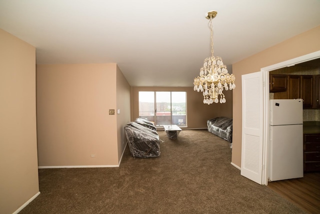 unfurnished bedroom with dark carpet, white fridge, and a notable chandelier