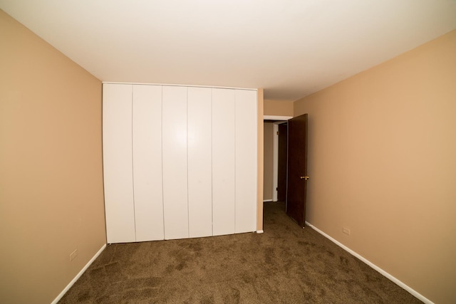 unfurnished bedroom featuring dark carpet and a closet