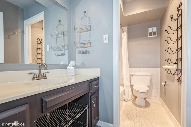 bathroom featuring tile patterned floors, vanity, toilet, and tile walls