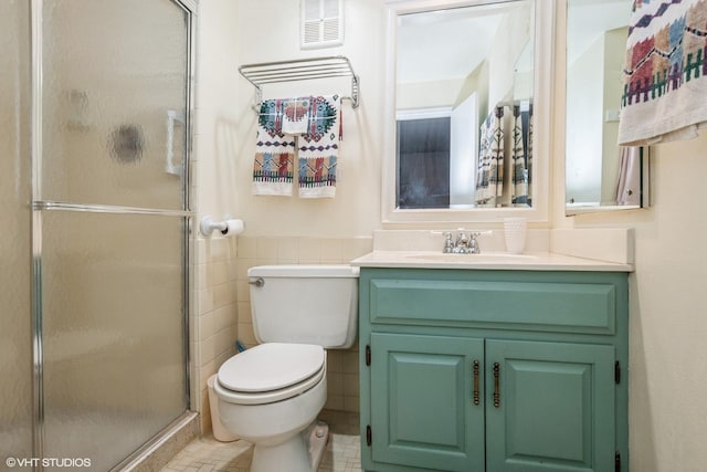 bathroom featuring a shower with door, vanity, tile walls, and toilet