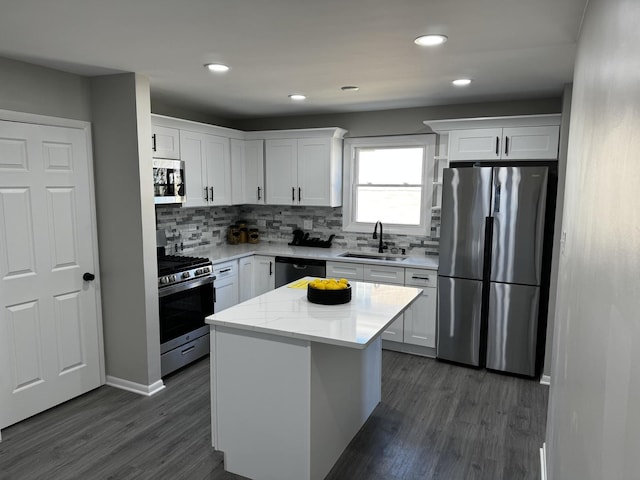 kitchen with white cabinets, decorative backsplash, dark wood-type flooring, stainless steel appliances, and a sink