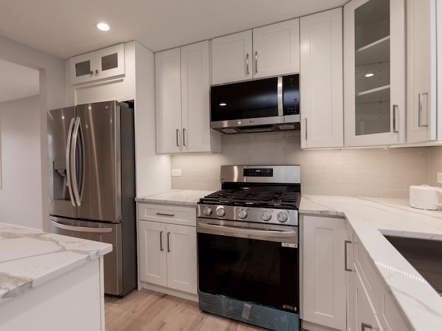 6310 Hilly Way, Cary, IL 60013 - kitchen featuring appliances with stainless steel finishes, white cabinets, decorative backsplash, light wood-style flooring, and light stone counters