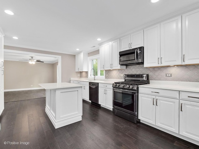 kitchen featuring appliances with stainless steel finishes, white cabinets, decorative backsplash, ornamental molding, and a center island