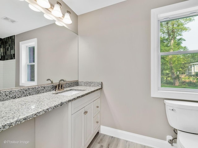 bathroom featuring vanity, hardwood / wood-style flooring, toilet, and a healthy amount of sunlight