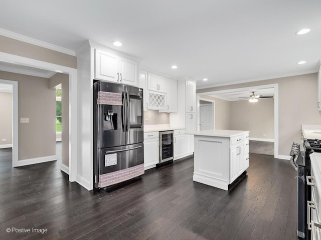 kitchen featuring wine cooler, ornamental molding, dark hardwood / wood-style flooring, stainless steel appliances, and white cabinets