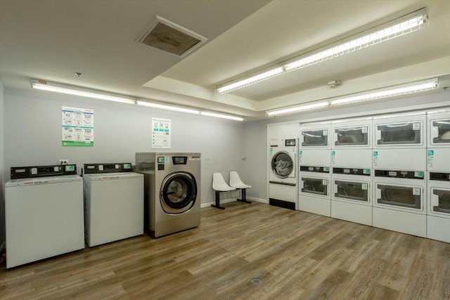 laundry room with stacked washer / dryer, independent washer and dryer, and light hardwood / wood-style floors