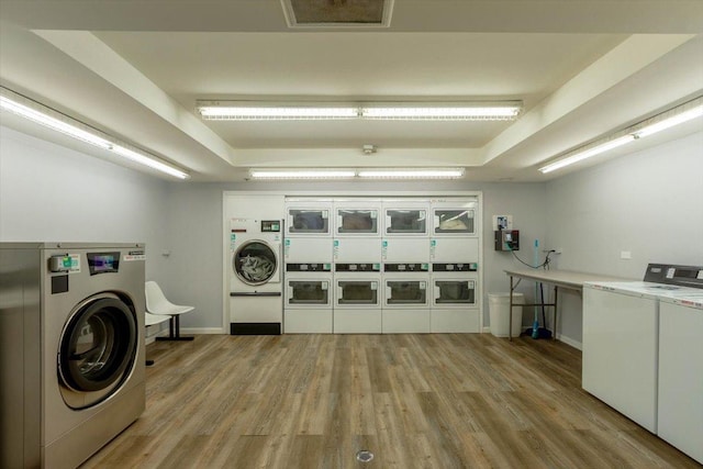 washroom featuring stacked washer and dryer, washing machine and dryer, and light hardwood / wood-style flooring