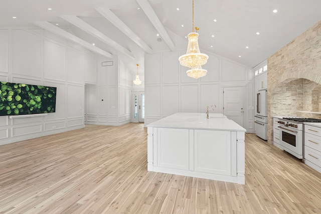 kitchen featuring sink, high end appliances, an island with sink, pendant lighting, and white cabinets