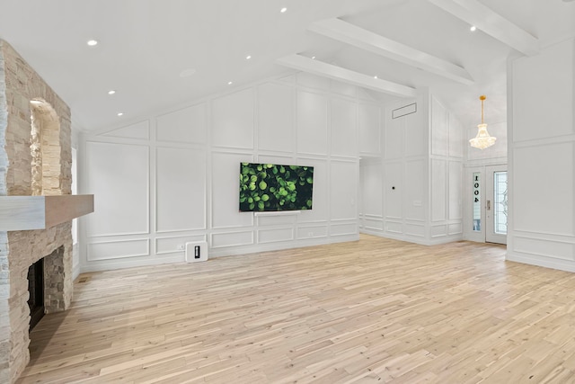 unfurnished living room featuring a stone fireplace, vaulted ceiling with beams, and light hardwood / wood-style floors