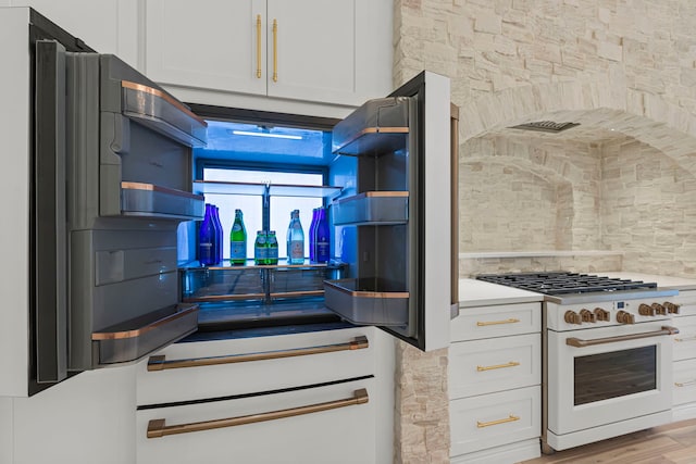 kitchen with white cabinetry, light hardwood / wood-style floors, tasteful backsplash, and white stove