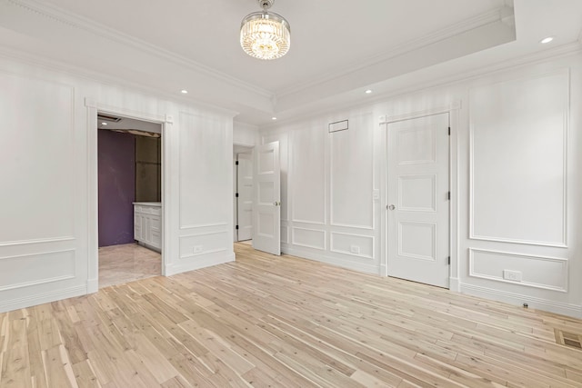 unfurnished bedroom with a tray ceiling, a chandelier, and light hardwood / wood-style floors