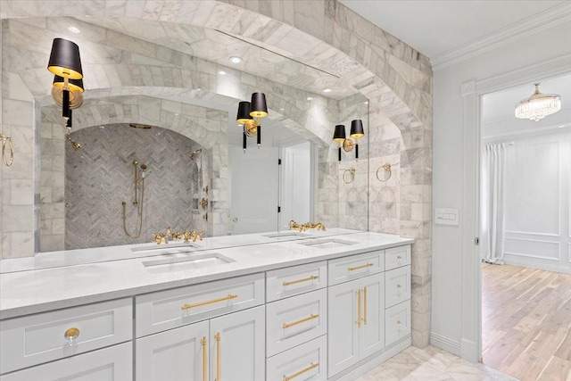 bathroom with ornamental molding, vanity, and a tile shower