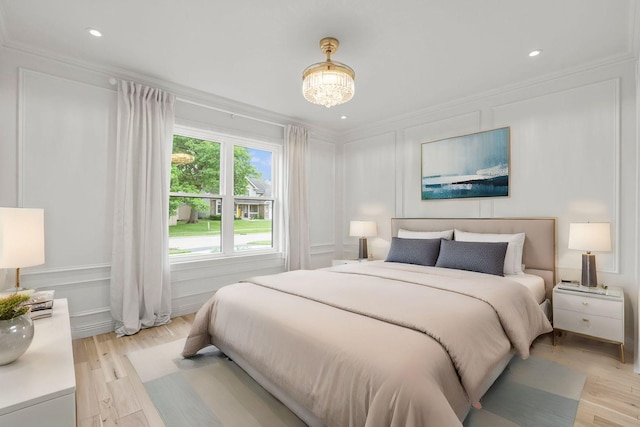 bedroom with a notable chandelier, ornamental molding, and light hardwood / wood-style floors