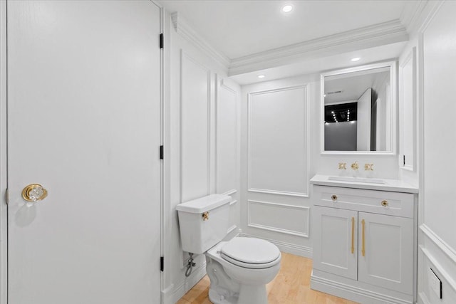 bathroom featuring vanity, hardwood / wood-style floors, crown molding, and toilet