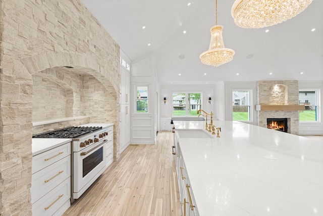 kitchen featuring hanging light fixtures, white cabinetry, a notable chandelier, and high end range