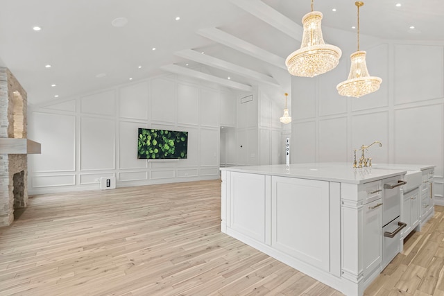 interior space with lofted ceiling, sink, a stone fireplace, and light hardwood / wood-style flooring