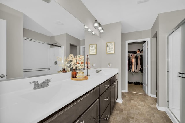 bathroom featuring a shower with door and vanity