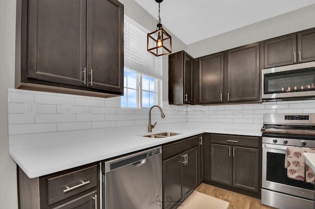 kitchen featuring dark brown cabinetry, appliances with stainless steel finishes, sink, and hanging light fixtures