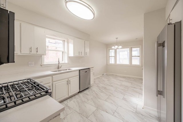 kitchen with pendant lighting, sink, stainless steel appliances, a wealth of natural light, and white cabinets