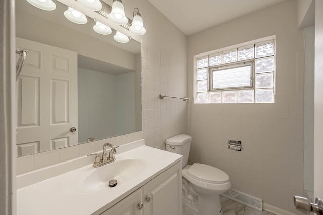 bathroom featuring vanity, tile walls, and toilet