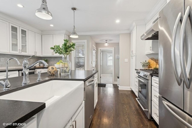 kitchen featuring pendant lighting, exhaust hood, white cabinets, and appliances with stainless steel finishes