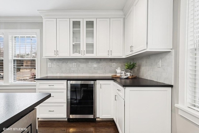 kitchen with white cabinetry, backsplash, beverage cooler, crown molding, and dark wood-type flooring