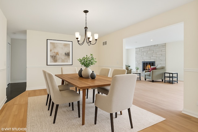1247 Highpoint Ln, Northbrook, IL 60062 - dining area with light wood-style flooring, a chandelier, a stone fireplace, and baseboards